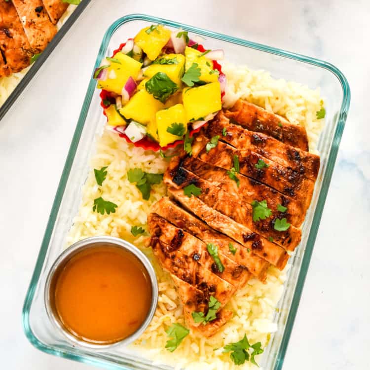 chipotle lime chicken meal prep in a glass rectangle container with mango salsa and dressing.