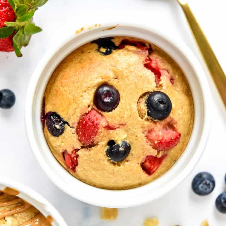 Individual air fryer baked oats in a white ramekin with berries.
