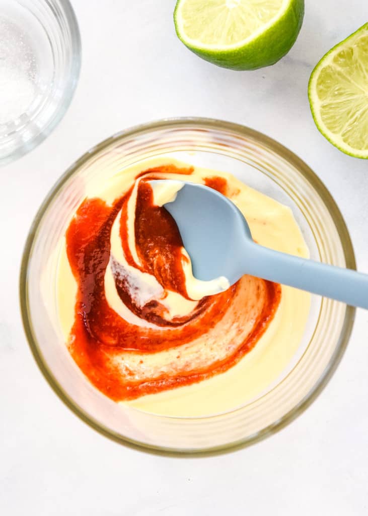 stirring together the mayo and sriracha sauce in a glass bowl.