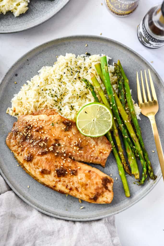 ginger soy tilapia with broiled asparagus on a grey plate with lime.