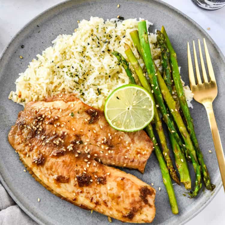 ginger soy tilapia with broiled asparagus on a grey plate with lime.