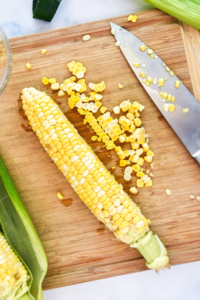 cutting corn from the cob on a cutting board.