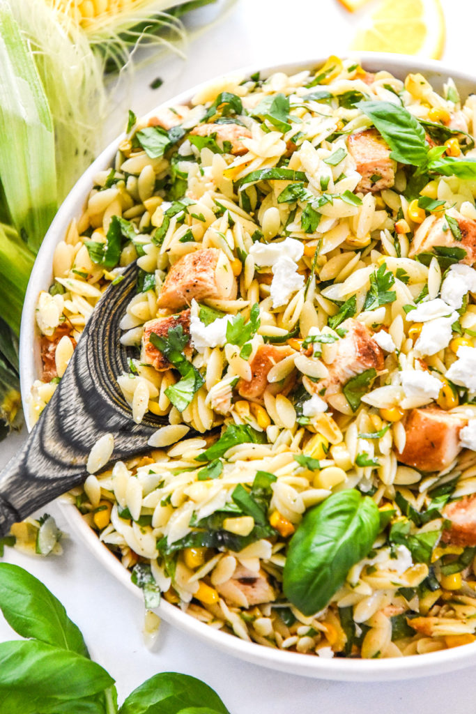 lemony chicken and corn orzo salad with fresh herbs and crumbled goat cheese on top.