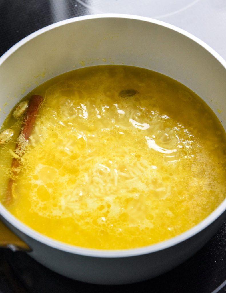 simmering turmeric rice in a small pot with a cinnamon stick.