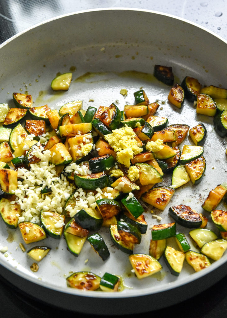 browned zucchini with ginger and garlic in a pan.