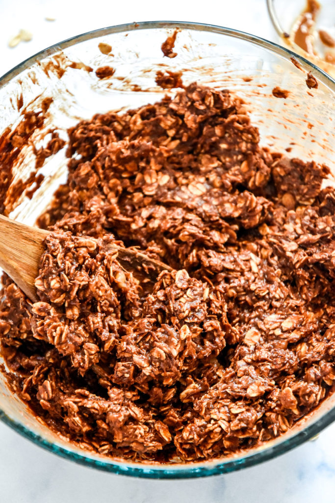 mixed batter for the banana chocolate oatmeal mounds in a glass bowl with wooden spoon.