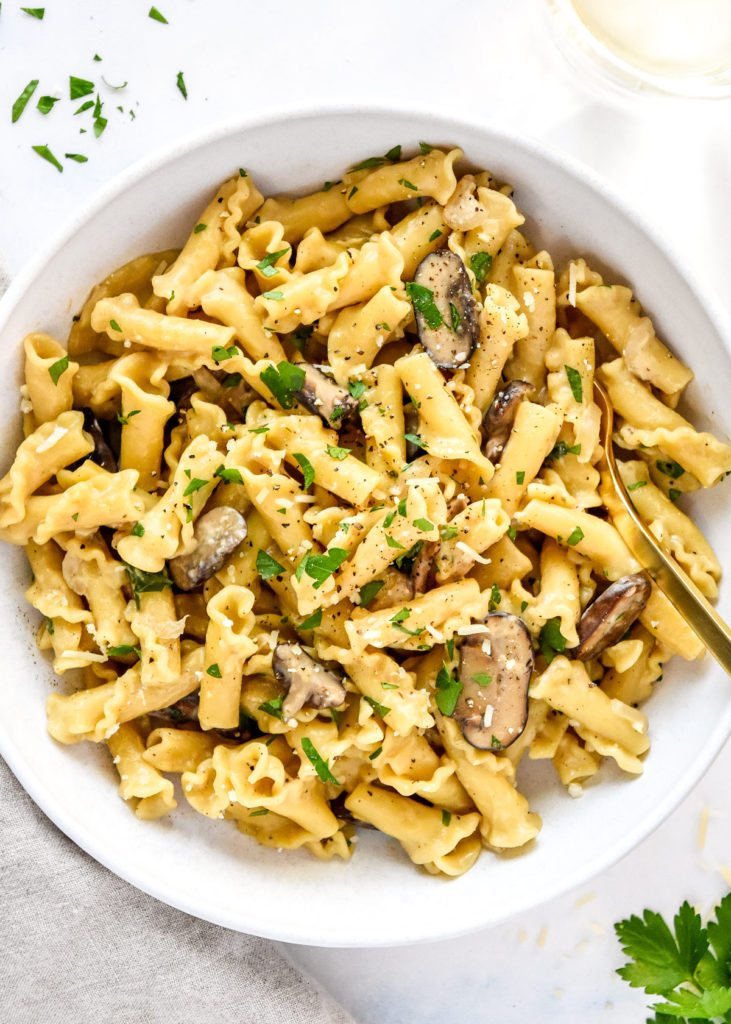 a bowl of one pot creamy mushroom pasta with parmesan cheese and parsley on top.