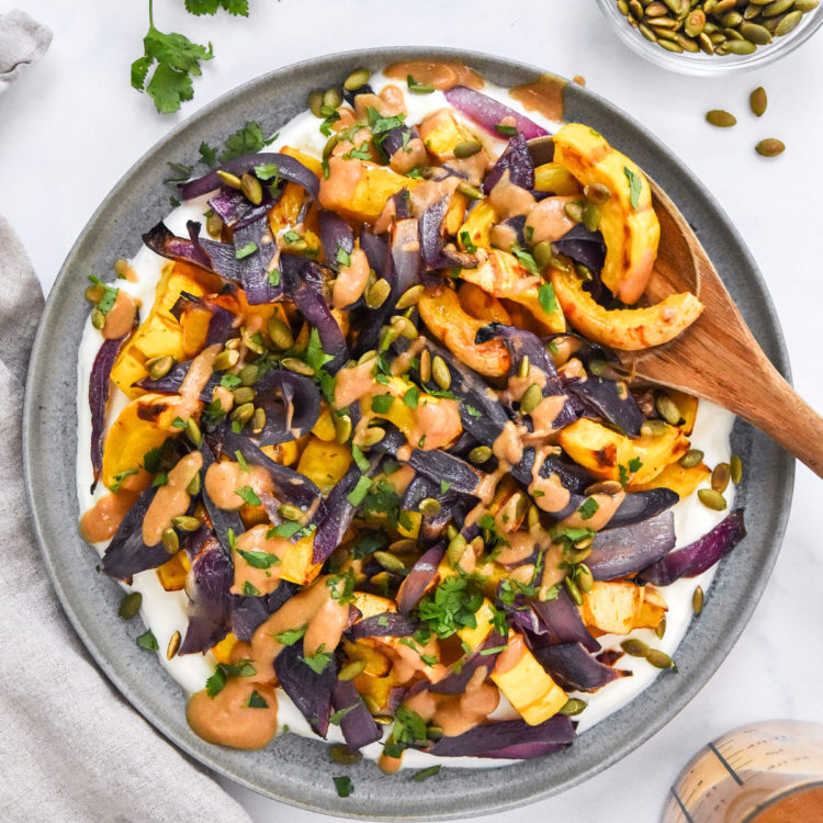 roasted squash salad with whipped feta on a plate with a wooden spoon.