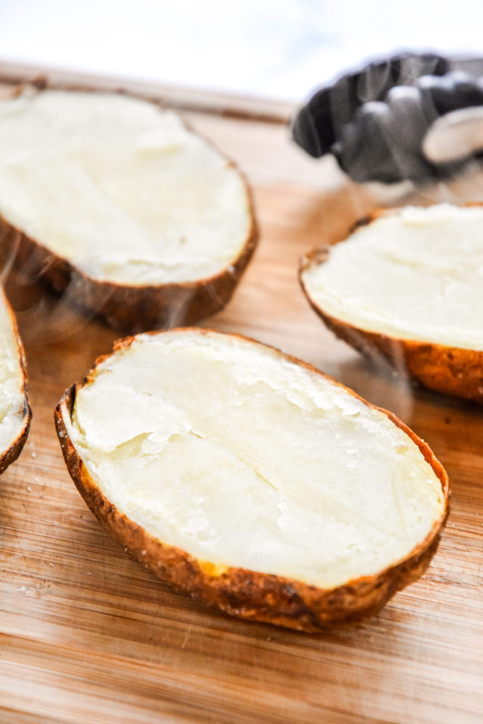 baked potatoes sliced in half on a cutting board.