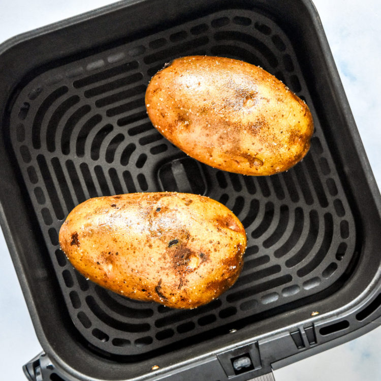 raw russet potatoes in the air fryer basket before baking.