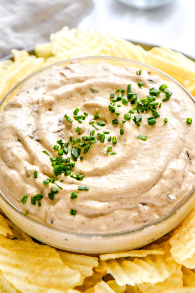 homemade roasted onion dip with chives on top in a serving bowl.