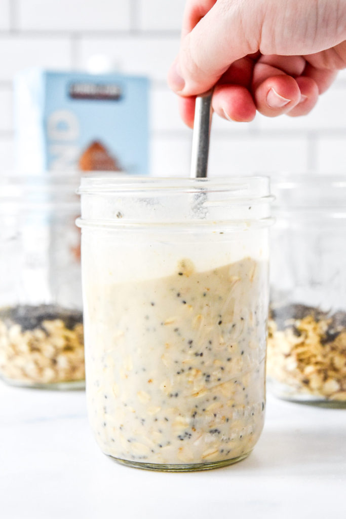 stirring a mason jar full of protein overnight oats base recipe.