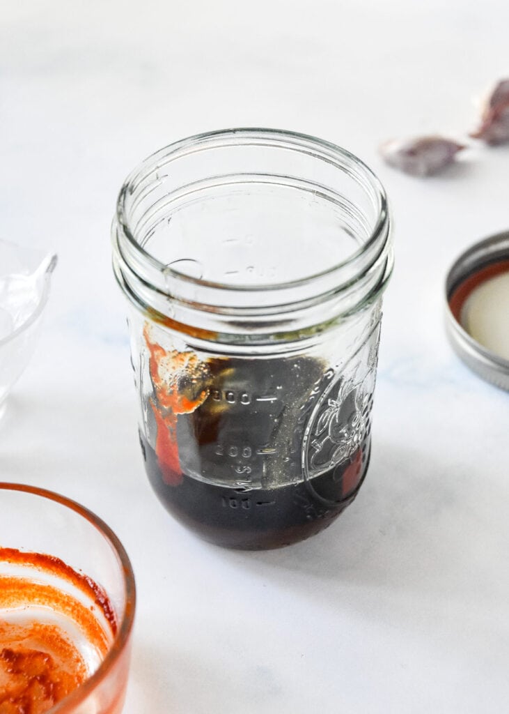 mason jar with soy sauce and other sauce ingredients inside.