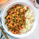 Korean-Inspired Gochujang Meat And Beans in a white bowl with rice and a fork.