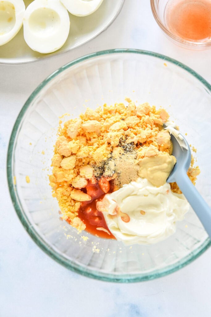 egg yolks removed from hard boiled eggs in a bowl with mayonnaise.