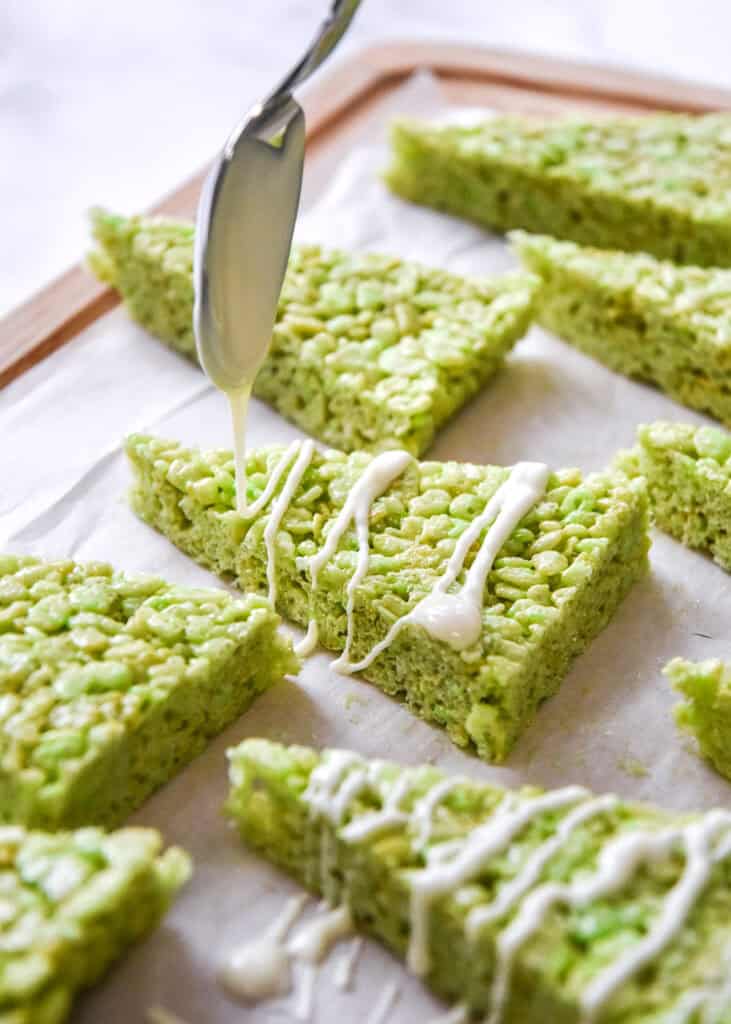 drizzling white chocolate on the green rice krispies triangles.