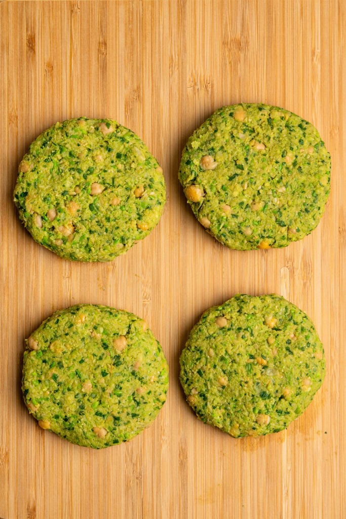 herby chickpea veggie burgers on a cutting board before cooking.