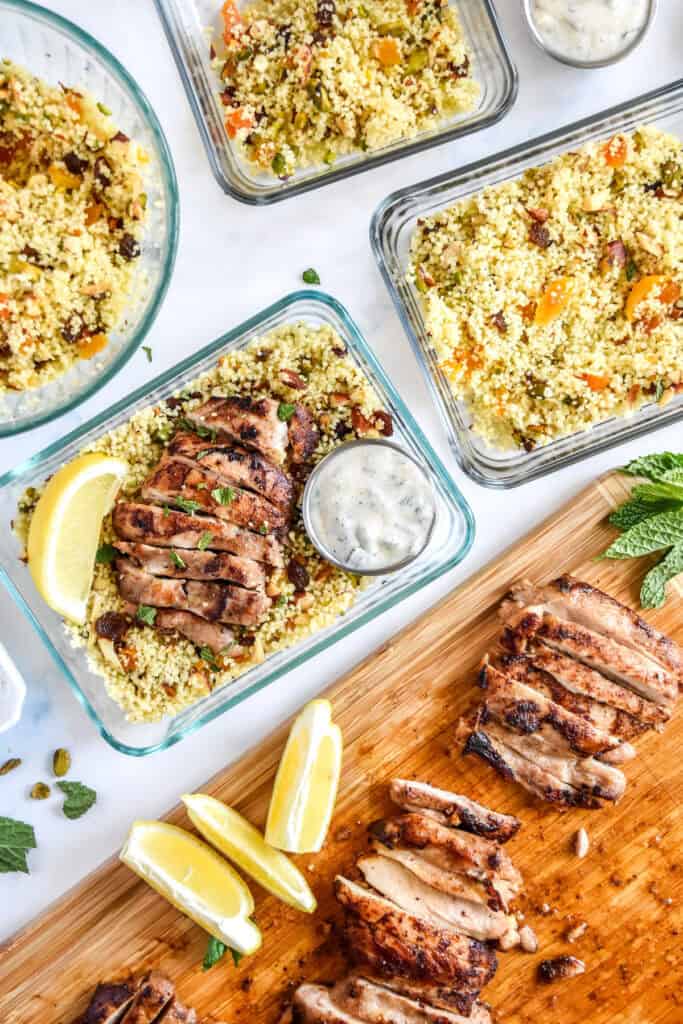 assembling the moroccan-inspired spiced chicken couscous bowls into glass meal prep containers.
