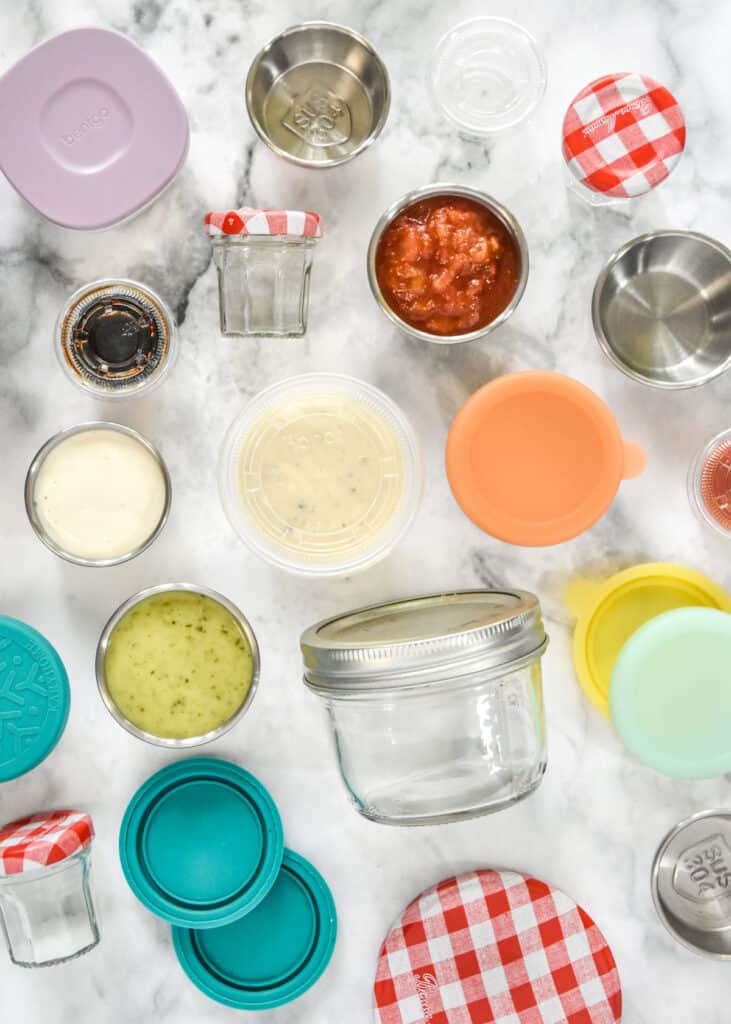 several kinds of sauce and dressing cups for packing with meal prep lunches.