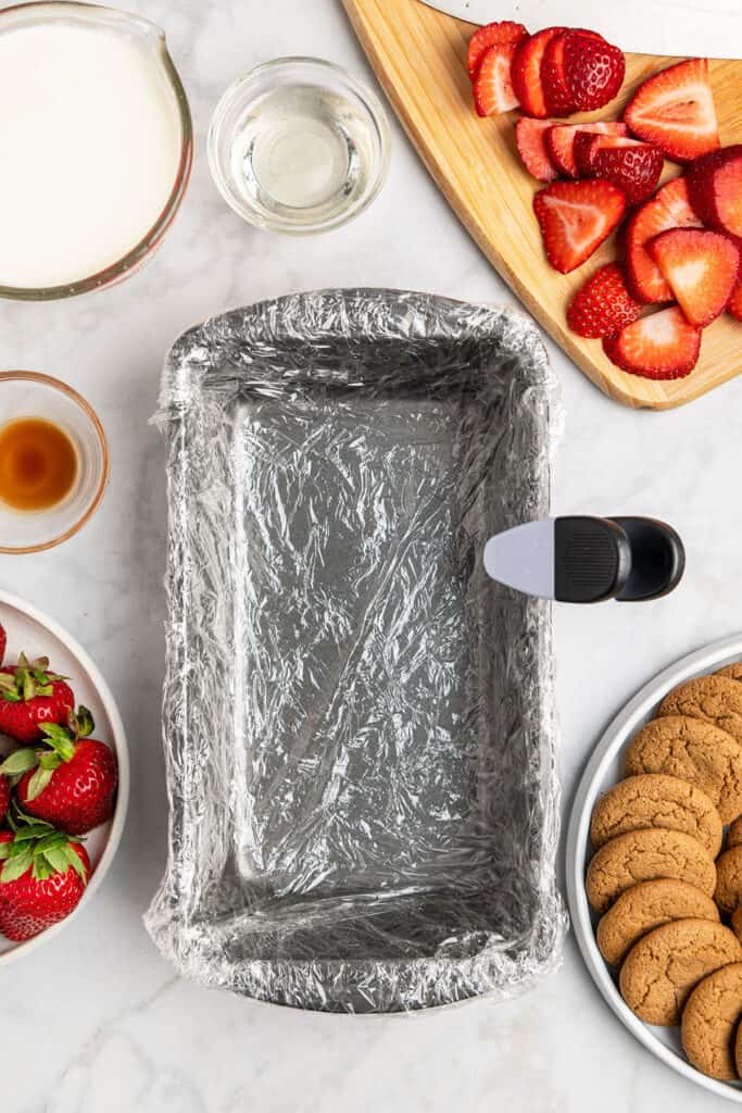 top view of a loaf pan lined with plastic wrap and secured with a chip clip.
