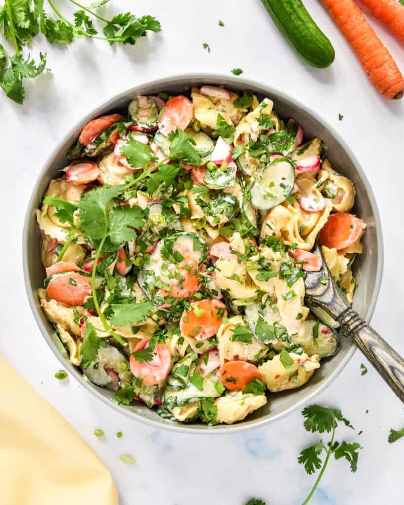 banh mi inspired tortellini salad in a large serving bowl with wooden spoon.