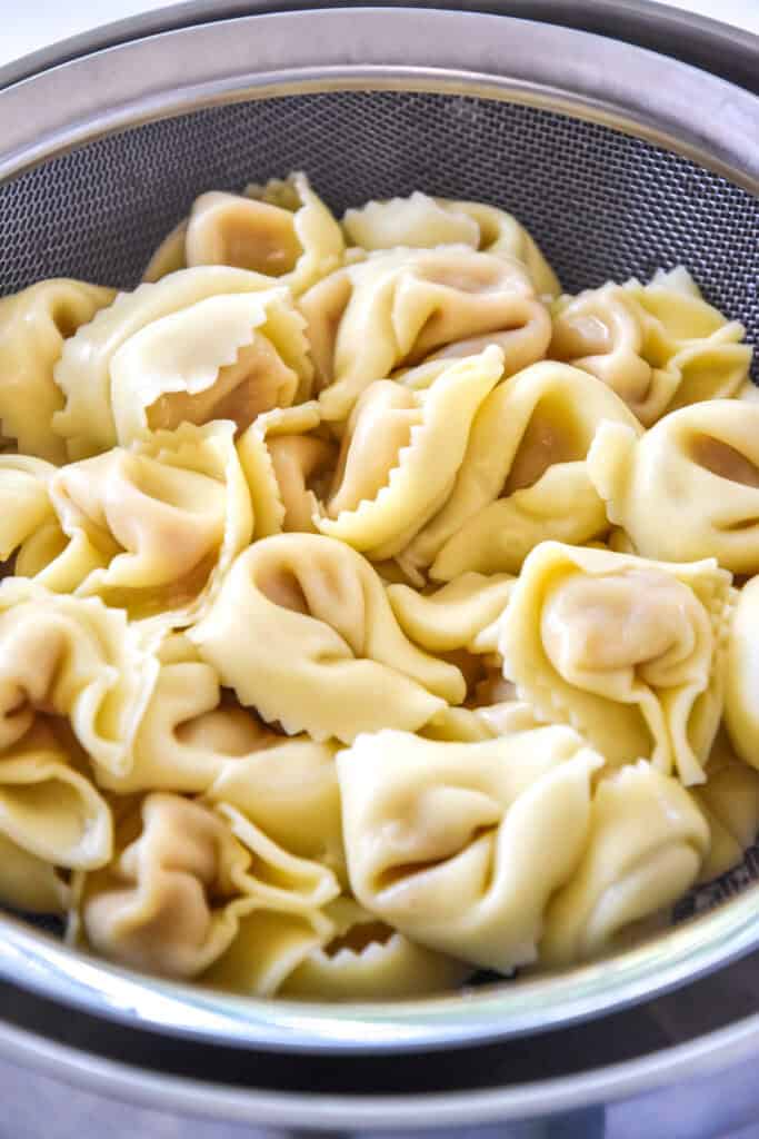 cooked tortellini in a strainer basket.