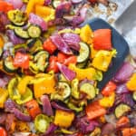 Easy Oven Roasted Summer Vegetables on a sheet pan with spatula.