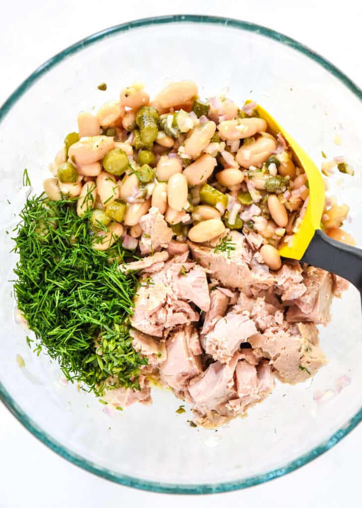 french style white bean tuna salad with herbs and beans before mixing in a glass bowl.