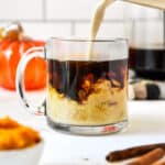 pouring homemade pumpkin spice coffee creamer into a cup of black coffee.